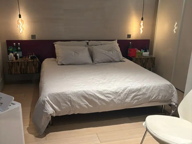 Bedroom with a made double bed, pendant lights and a dark headboard