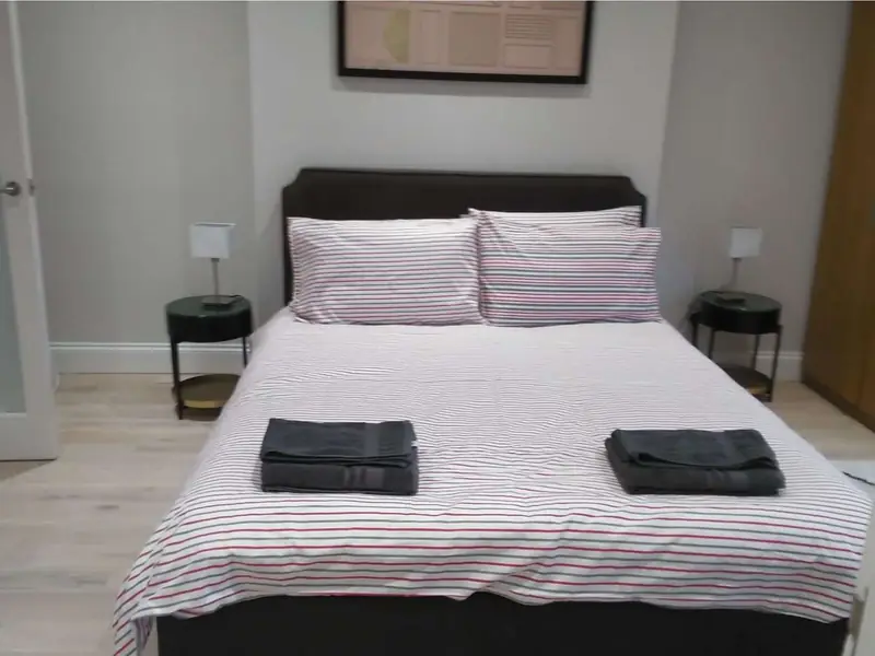 Double bed made with striped linen and folded towels on top
