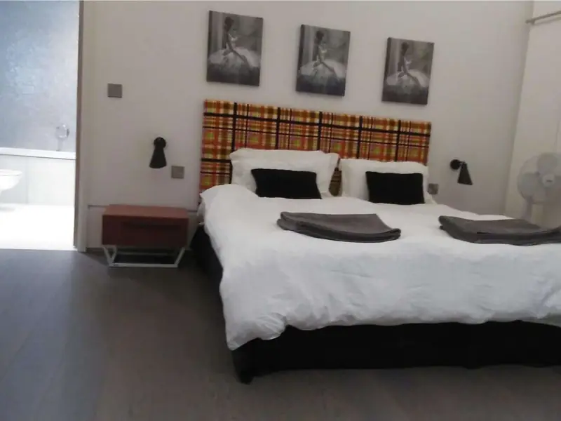 Bedroom with white bed linen, folded towels and an en-suite door