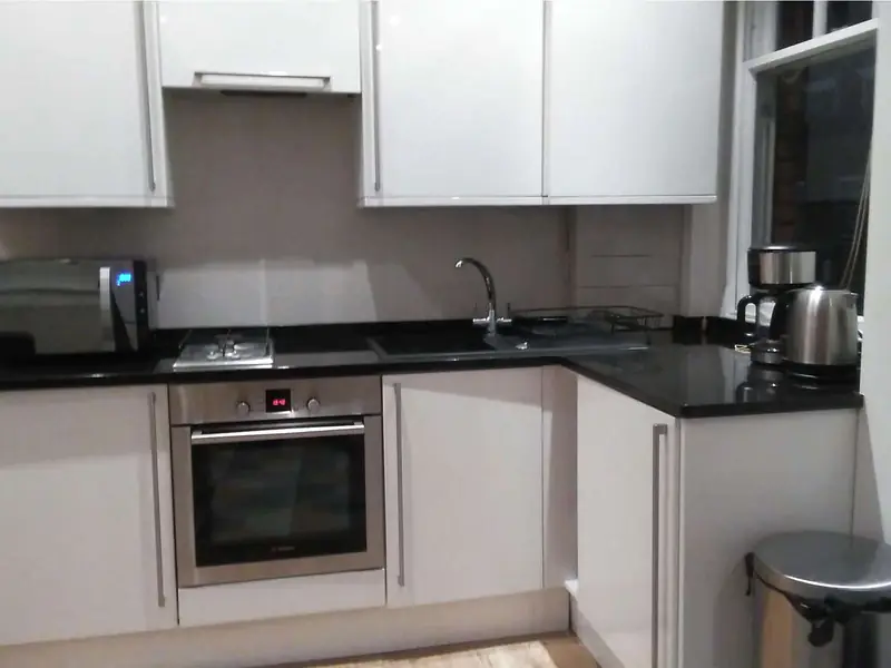 Compact kitchen with white units, black worktop, oven and hob