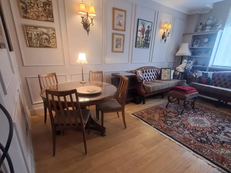 Dining room with a round table, panelled walls, wall lights and a Persian rug