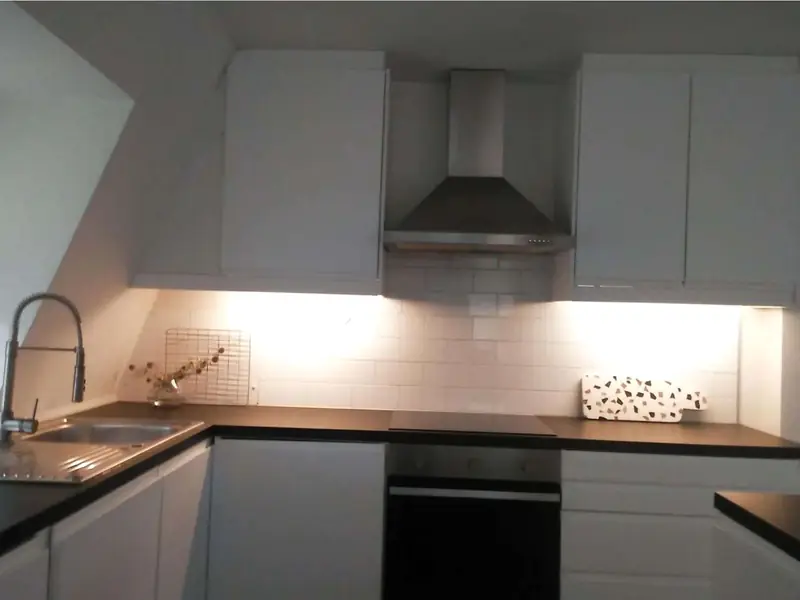 Kitchen with white units, black worktops, tiled splashback and extractor hood
