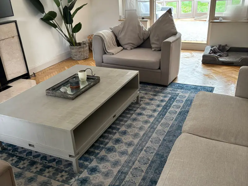 Living room with a large coffee table, blue patterned rug, armchair and herringbone floor