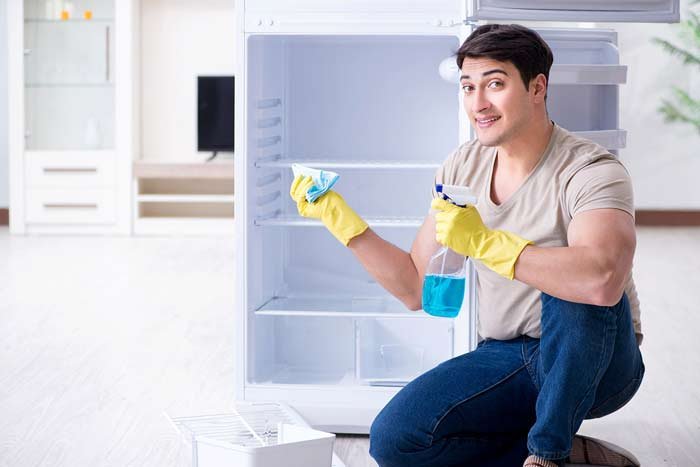 man cleaner spraying and cleaning a fridge